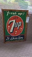 Front view of handmade wooden sign painted with vintage 7up advertisement text and logo, showing entire sign framed in wood.