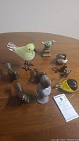 Photo showing overview of nine bird figures and two mouse figures assorted on a wooden table.