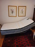 Side view of single adjustable bed frame with Kingsdown mattress angled, remote control visible