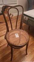 Full view of antique bentwood chair showing curved wooden backrest and woven cane seat.