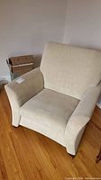 Front view of beige upholstered armchair with wide armrests