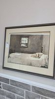 Image showing a framed picture of a dog lying on a bed inside a room with a window.
