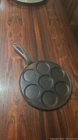Top-down view of cast iron pancake pan showing seven circular pancake molds.
