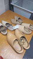 Four pairs of Dutch shoes including traditional and wooden clogs placed on a wooden table.
