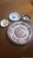 Photo showing all four items: large red and white decorative plate, blue and white bird plate, small white and gold floral dish, and round white and gold candle holder.