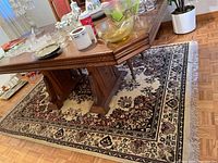 Full view of the rectangular floral motif area rug under a wooden table, showing primary aesthetic and border design.