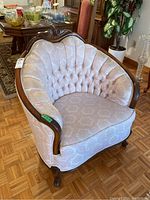Side view of upholstered arm chair showing floral patterned fabric and curved wooden frame with carved top detail and cabriole legs.