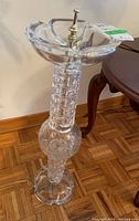Full view of the cut glass ashtray stand showing top scalloped ashtray bowl with metal finial and detailed cut glass cylindrical stand with floral motif on the round central part.