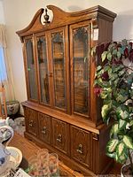 Full view of the wood buffet and hutch with glass front doors and ornate wood details, showing the lower buffet section with four decorative wooden doors and upper hutch with four glass front doors with decorative etching and top finial.