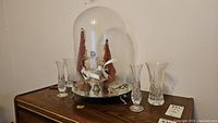 Full view of the mirrored cloche with crown and four crystal vases on a wooden surface