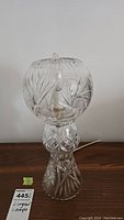 Full view of one pinwheel cut crystal lamp on wooden surface showing overall shape and design pattern.