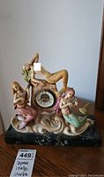 Front view of the Depose Italian mantle clock on a marble base with three colorful mermaids surrounding the clock face.