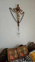 Photo of ceramic Jesus on cross with oversized wood bead rosary draped on it, showing the design and condition of the cross and rosary.
