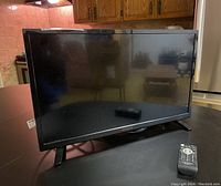 Front view of a 24-inch Insignia television on a stand with remote placed beside it.