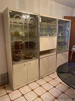 Front view of the three-section wall unit showing glass display cabinets above and storage cupboards below.