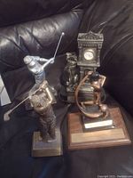 Four golf trophies on black leather couch showing variety of designs