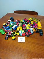 Overall view of entire lot of toy vehicles arranged on a table showing variety and quantity.