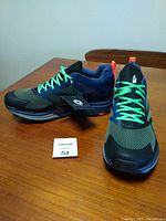 Pair of men's The North Face trail running shoes, size 12, displayed on a table showing side and front view with tags still attached.