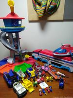 Photo showing Paw Patrol Lookout Tower, Air Patroller vehicle, several character vehicles, and figures grouped on a wooden surface.