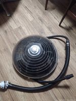 Top view of the solar dome heater with attached hose coiled on wooden floor.