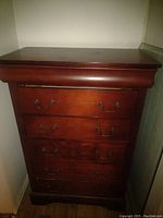 Front view of the tallboy dresser showing all five drawers closed, showcasing the dark wood finish and metal handles.