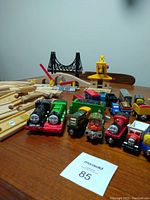 Multiple Thomas the Tank Engine wooden trains and track pieces including bridge and crane visible on a table.