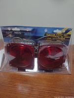 New in box Optronics trailer light set with two red square lights in black mounting frames.