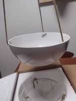 White ceramic hanging planter suspended by beige cords, shown from side angle to display bowl shape and attachment points.