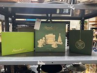 Three green boxes showing Department 56 Snowbabies figurines and gift bag on a shelf
