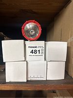 Top view of flashlight lens and five white boxes stacked below