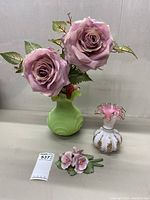 Full shot of the three items: green glass vase with faux pink roses, small pink and white ruffled vase, porcelain flower figurine