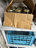 Box with multiple Ball mason jars packed inside with gold metal lids visible