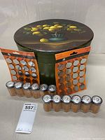 Large painted round container with lemon design lid on table with batteries in front: 12 D batteries and two unopened packs of CR2450 button cells.