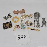 Photo showing mixed lot of 12 brooches and pins including animal and floral motifs, rhinestones, enamel and metal accents