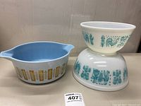 Photo of the Pyrex Delphite Blue casserole bowl with gold leaf and two nested Butterprint bowls showing graphics and colors.