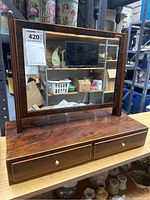 Front view of the wooden tabletop mirror showing the rectangular mirror and two drawers with brass knobs.
