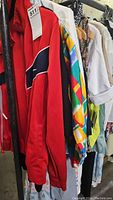 Photo showing red Nike jacket and colorful geometric printed clothing on rack