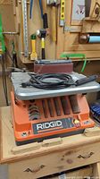 Front view of Ridgid oscillating belt sander mounted on cabinet with sanding belt on platen