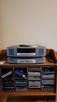 Front view of Bose Wave Music System stacked atop wooden CD rack filled with CDs