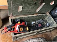 Chainsaw and its wooden carrying case opened, showing the tool inside.