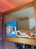 Theraband kit box and beige bath mat inside a wooden cabinet