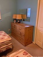 Front view of the pine dresser with six drawers, showing the brass drawer handles and the wear marks on the surface. Two lamps placed on top but not included in sale.