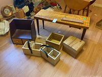 Wide shot of the cribbage table and smaller cribbage board with wooden boxes positioned around on floor