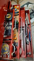Photo showing upper tool chest drawer with various pliers, screwdrivers and hand tools laid out inside red tool chest drawers with metal handles