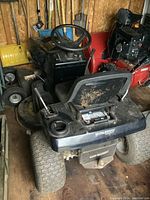 Rear and top view of black Murray ride-on mower in wooden shed