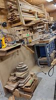 Wide view of stacked and hanging scrap wood on shelves and workbench showing variety of lengths and types