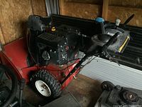 Side view of red Toro snow blower showing engine, housing, wheels and handlebars