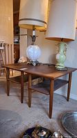 Pair of teak end tables side by side with lamps on top, view of tables and upper surfaces