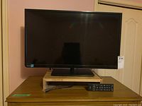 Front view of Toshiba 32-inch TV on stand with remote control in front.