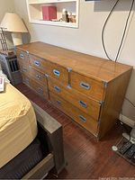 Full view of antique Bernhardt dresser placed next to bed, showing seven drawers and solid wood construction with metal pull handles.